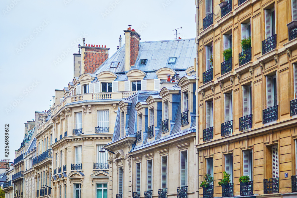 Fototapeta premium Parisian apartment buildings with Haussmann-style facades, mansard roofs, balconies, and elegant historic architecture in France.