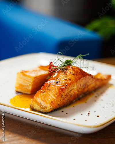 Gourmet glazed salmon fillet served with layered potato gratin and delicate microgreens