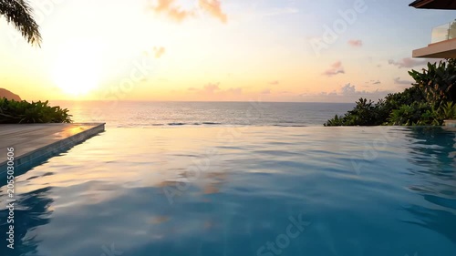 Serene infinity pool overlooking calm ocean waters at sunset with lush greenery and tropical trees in the background.