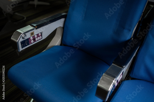 Schilderij op canvas Close view of empty blue passenger seats with armrests and control panel inside a modern train or bus, showing clean public transport interior and comfortable travel