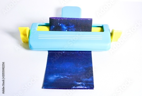 Konstfotografi Blue and yellow paper crimper art and craft tool with blue scrapbook paper isolated on white background