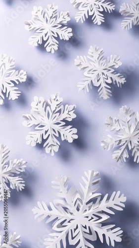 White paper snowflakes arranged on a pastel purple background create a festive and elegant winter scene. Delicate cut out patterns evoke a sense of seasonal creativity and holiday spirit
