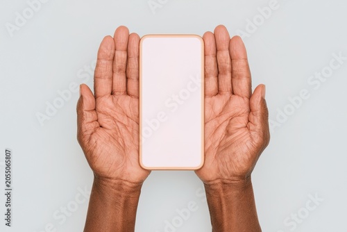 Hands gently holding a blank smartphone against a soft background