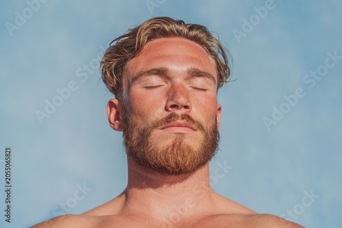 Sun-kissed man enjoys the warmth under a clear blue sky during summer