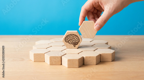 Hand placing blank wooden hexagon near brain icon block flat on wooden table