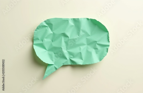Green crumpled paper speech bubble isolated on light background. Empty conversation cloud for text messages and communication ideas. Simple design element.