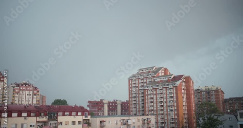 Moody urban cityscape with a distant thunderstorm and rain approaching over redbrick apartment towers.