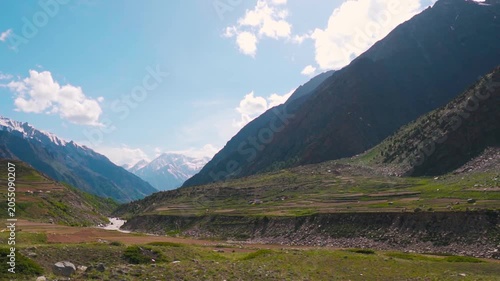 Landscape shot of snowy Himalayan mountain peaks with clouds above them during the summer season as seen during the Miyar Valley Trek in Lahaul, Himachal Pradesh, India. Scenic view of mountain valley