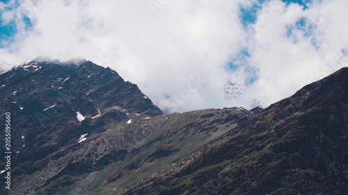 Landscape shot of clouds covering the snowy Himalayan mountain peaks during the summer season as seen from Mulling village in Lahaul and Spiti district, Himachal Pradesh, India. Scenic natural view.