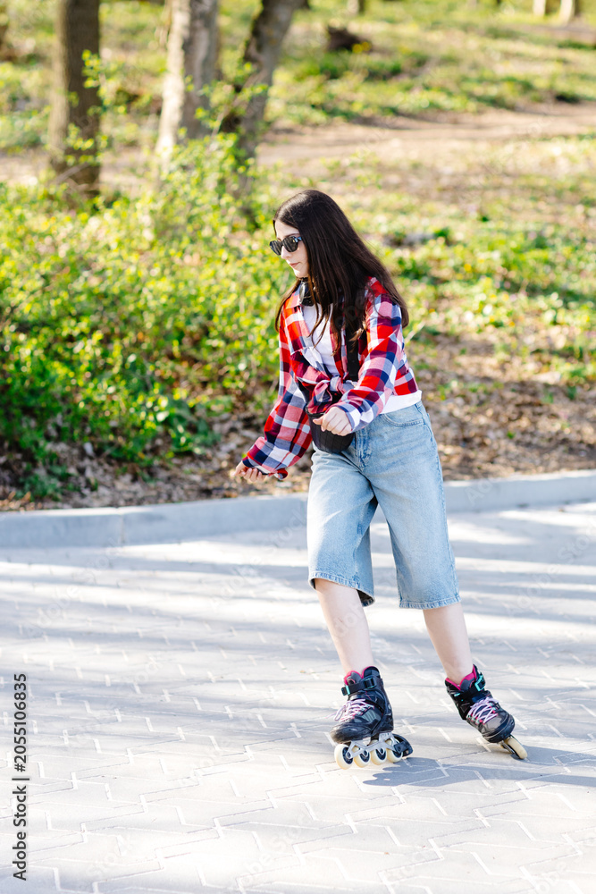 Fototapeta premium Young woman roller skating in a park during spring enjoying a sunny day