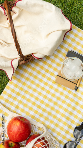 Picnic basket and apples on a yellow checkered blanket