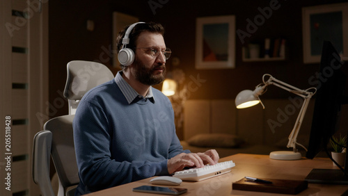 фотографія Man wearing headphones works at computer