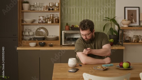 Medium shot of adult Caucasian man with diabetes sitting at table and injecting insulin into arm. Footage perfect for diabetes awareness campaigns and healthcare marketing