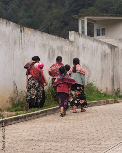 Zinacantan, Mexico; 1st January 2026: Indigenous Tzotzil women and children in traditional clothing walk down a village street in Chiapas.
