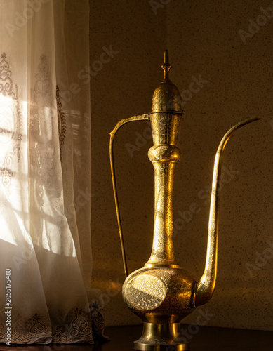Antique Moroccan brass teapot with ornate engravings placed by a window in Meknes