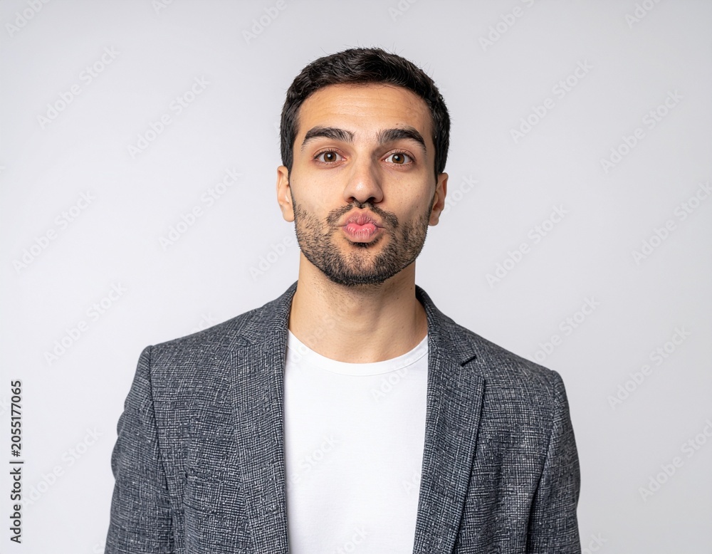 Obraz premium Close up portrait of a funny young male office worker puffing his cheeks isolated on white background for humorous business stress concepts.