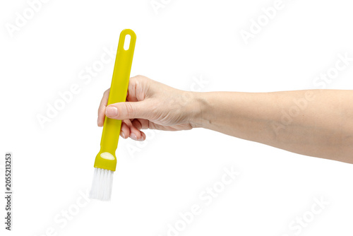 Woman's hand holding a cooking brush on the white background.