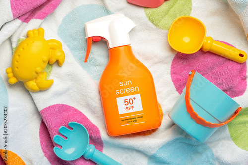 Top view of bottle of sunscreen 50+ and beach toys. Concept of sun protection