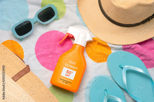 Top view of bottle of sunscreen with 50+ written on it,sunglasses and beach items. Concept of sun protection