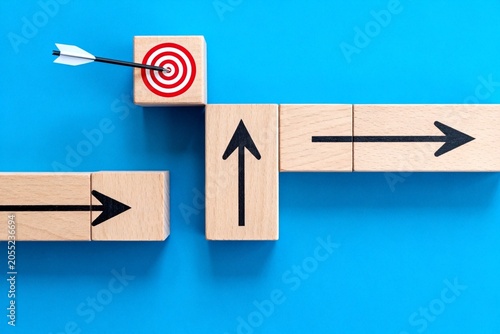 Wooden Blocks with Arrows Leading to Target on Blue Background