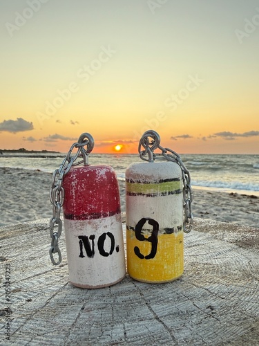 handmade small wooden buoys on the beach at sunset