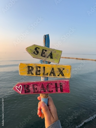 Signpost made of colorful wooden arrows by the sea at sunset