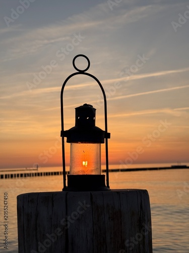 Rustic lamp with the setting sun over the sea