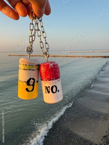 hand holding whimsical self created wooden buoys at the beach