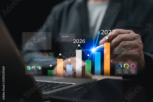 Businessman planning 2027 business goals, analyzing growth forecasts, investment performance, financial strategy, profit targets, and future success through data-driven charts and business plannin