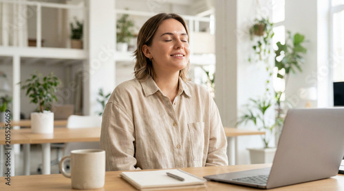 Young professional woman meditating at her desk, finding peace and calm in the workplace