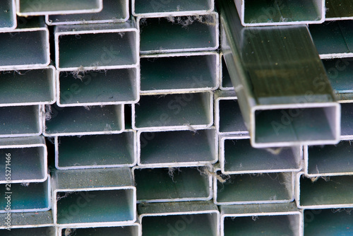 Close-up of stacked metal square tubes in industrial warehouse setting