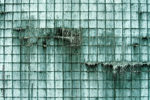 Weathered Green Tiled Wall with Water Stains and Cracks in an Urban Environment