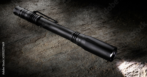 Small penlight flashlight on a large boulder