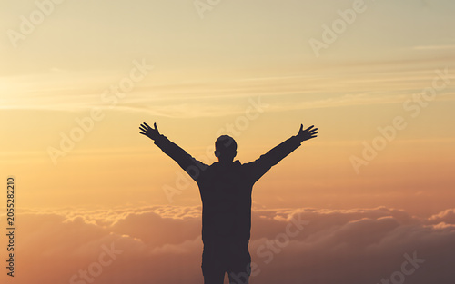 Silhouette of a man with arms raised against a sunset sky isolated on a transparent background