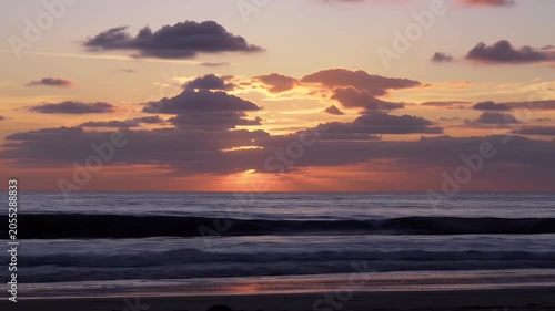 Dramatic Sunset Over the Ocean Horizon with Moving Clouds and Golden Reflections on Wet Sand