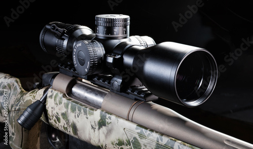 Large scope on a bolt action rifle with a dark background