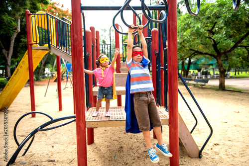 Canvastavla Two Asian children in superhero masks playing on jungle gym at park
