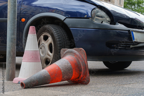 Damaged car front and traffic cones stand on a city sidewalk after an incident