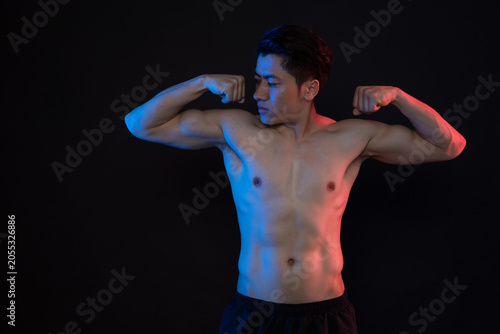 Foto Shirtless athletic man flexing muscles in dramatic blue and red studio lighting
