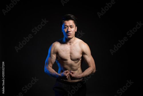 Foto Muscular shirtless man flexing in dark studio portrait