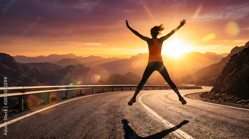 Fototapeta premium Joyful Woman Jumping on Scenic Mountain Road at Sunset Celebrating Freedom