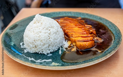 Breaded sliced chicken piece in sweet and source sauce, stewed rice on plate.