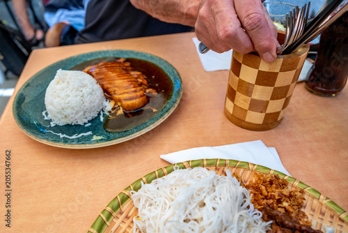 Restaurant table with two vietnamese meal and cup with cutlery.