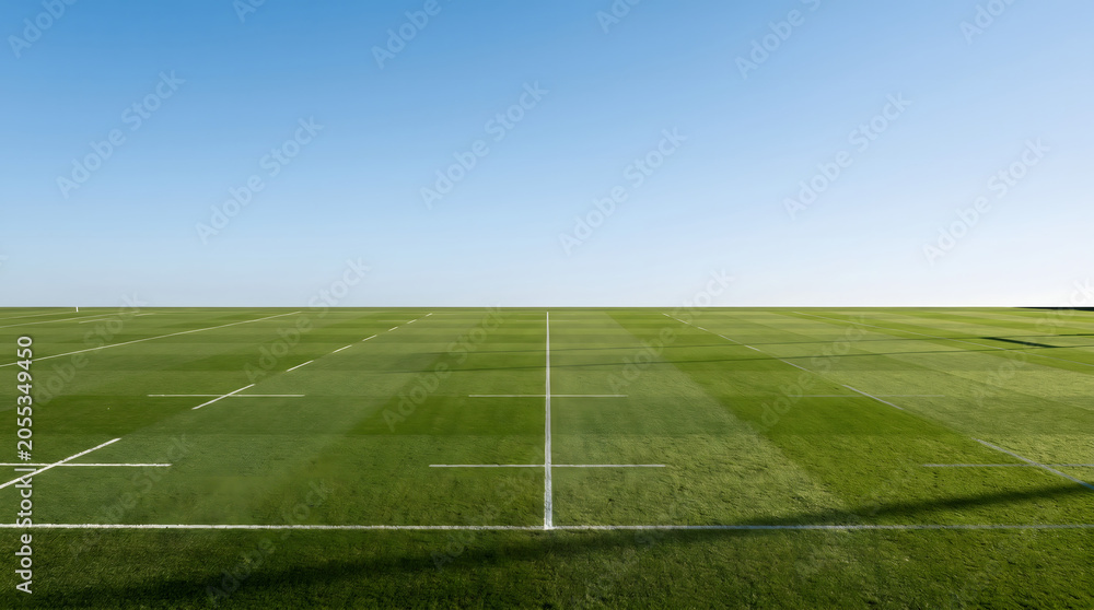 Obraz premium Empty rugby field with lush green grass under clear blue sky wide angle view