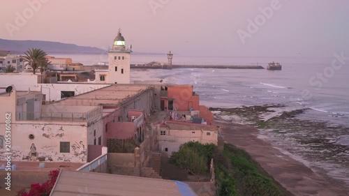 Sunset view over Sidi Ifni coast with lighthouse and waterfront buildings in Morocco