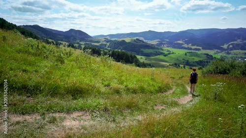 young woman trekking hiking meadows and hills with mountains view