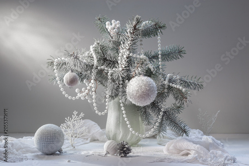 Winter still life with snow-covered spruce branches and Christmas decorations on a light background