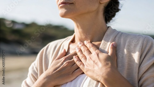 A person places their hands gently on their chest, symbolizing calmness and mindfulness in an outdoor setting.