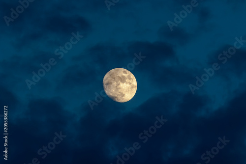 Foto Bright waxing gibbous moon surrounded by dramatic blue clouds in the evening sky