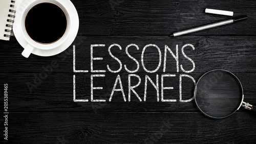 Lessons Learned Business Concept on Dark Wooden Desk with Coffee Notebook Magnifier and Pen for Project Review Strategic Analysis Knowledge Management and Professional Development